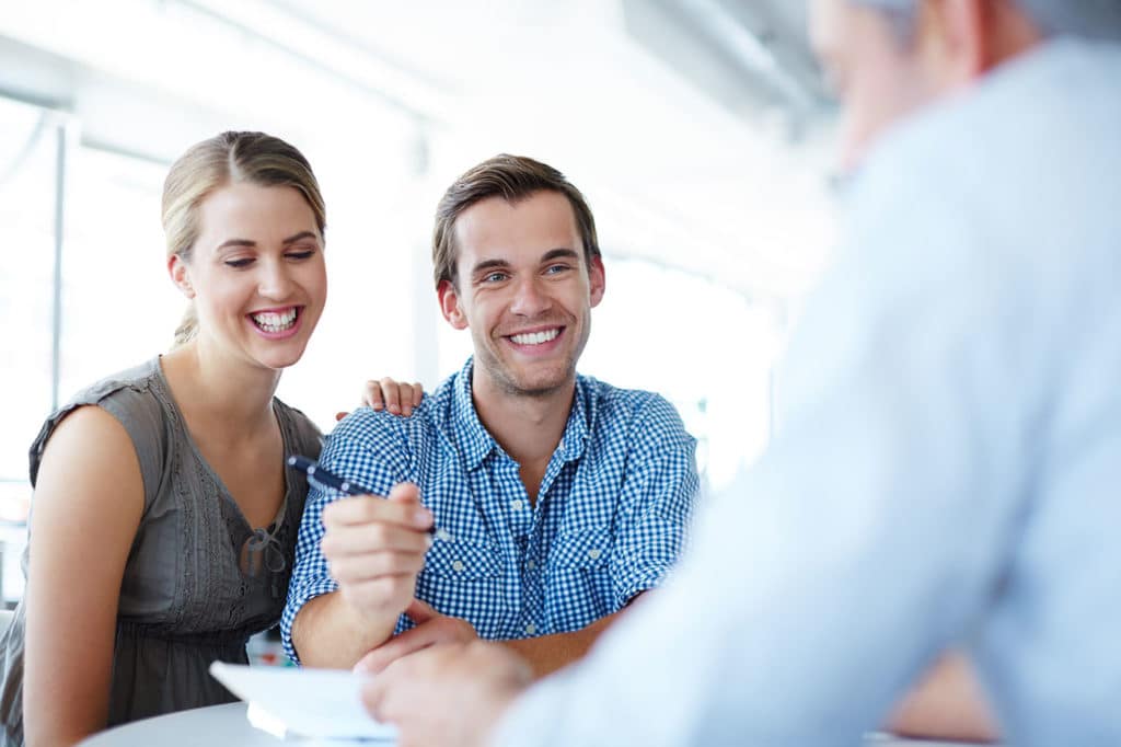 Smiling couple signing contract for basement waterproofing